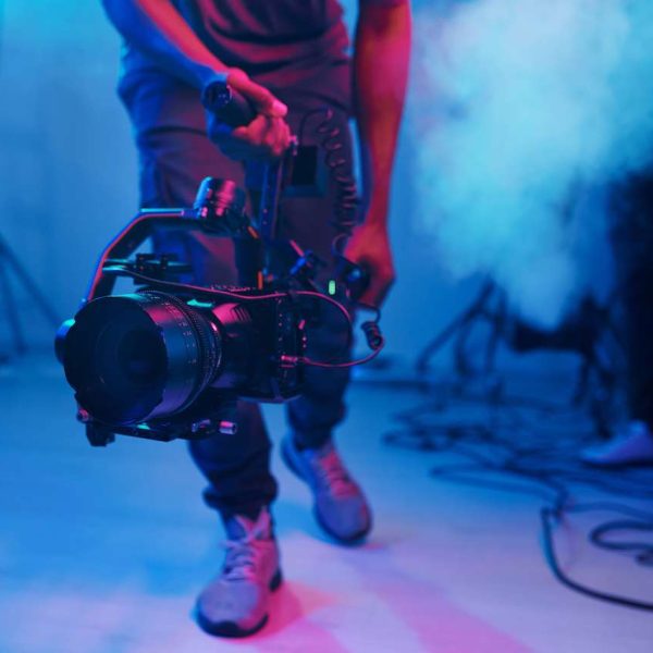 Close-up of cameraman using professional camera in shooting in studio