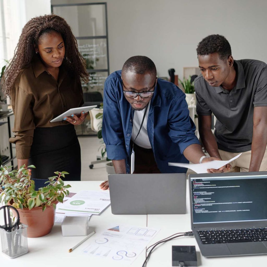 African American team of young and successful developers discussing and creating new codes in white office